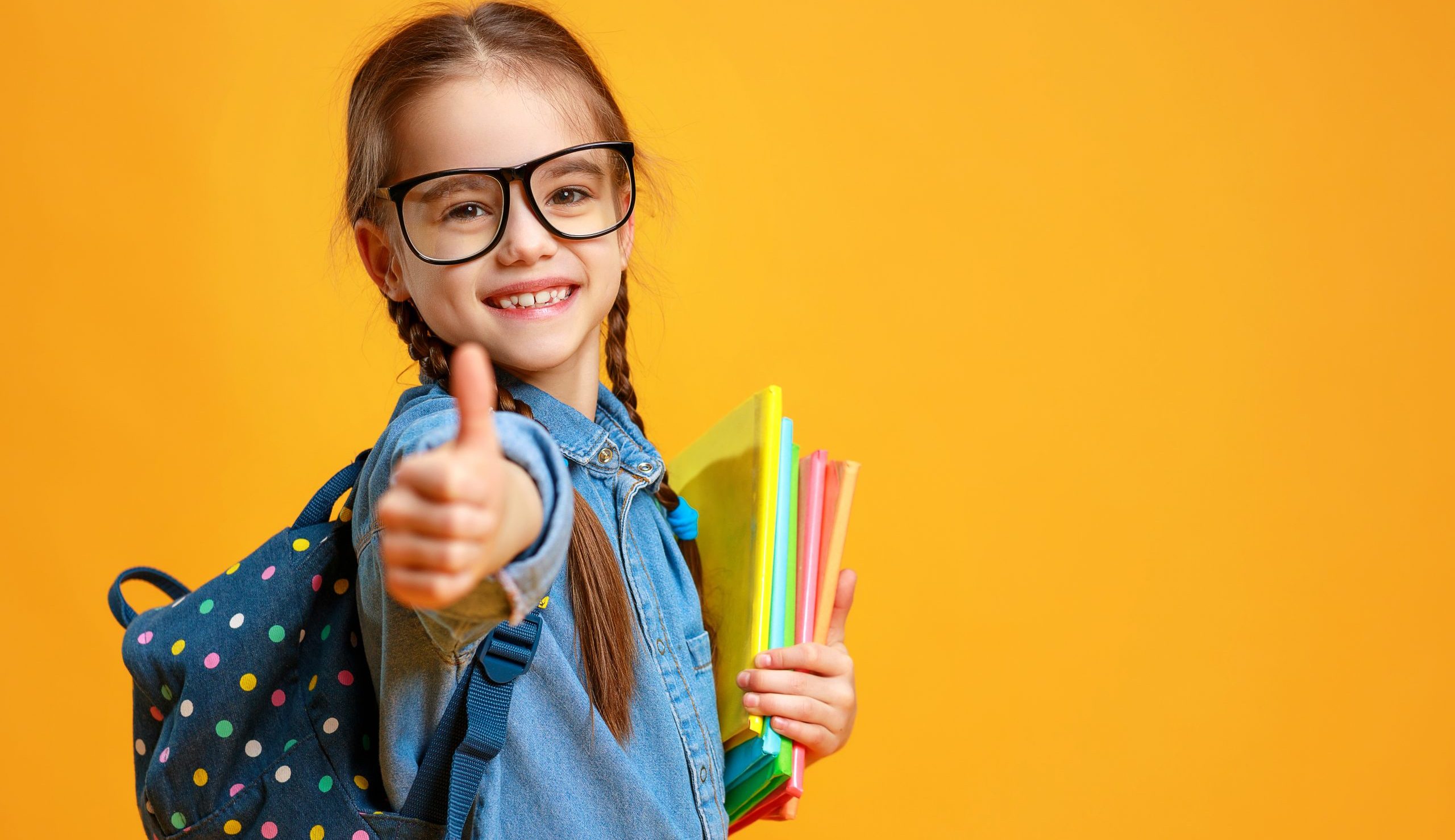 Child giving thumbs up with packback on ready to go back to school