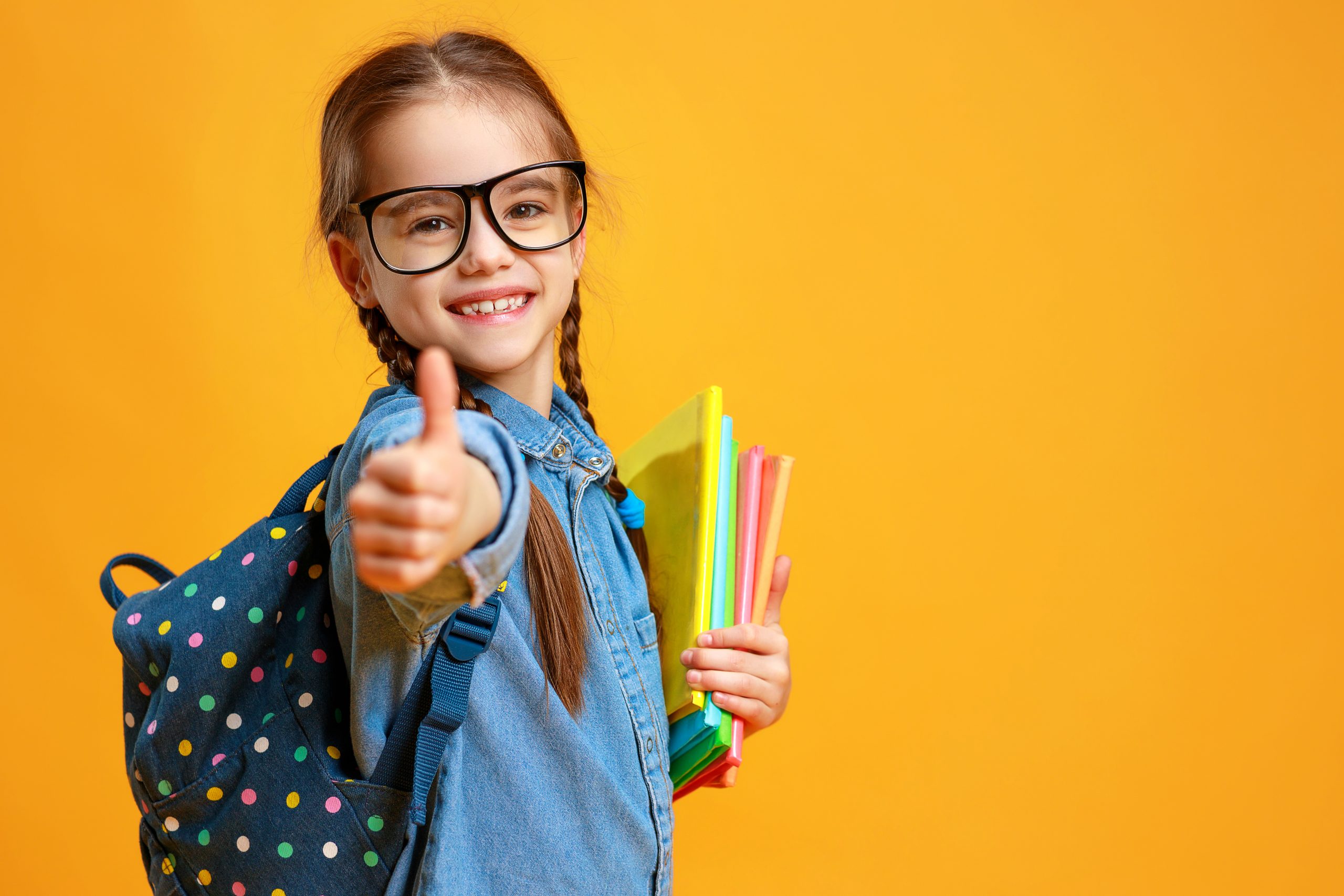 Child giving thumbs up with packback on ready to go back to school